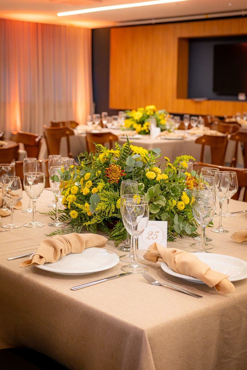 Mesa posta com arranjo floral amarelo e taças